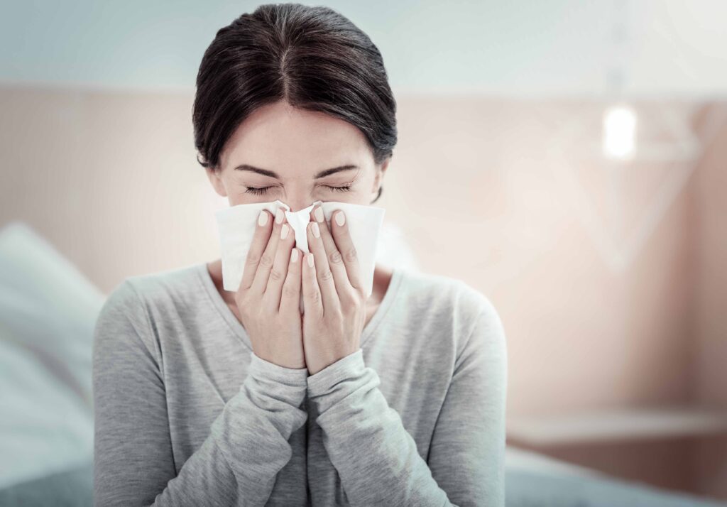 アレルギー反応で鼻をかんでいる女性